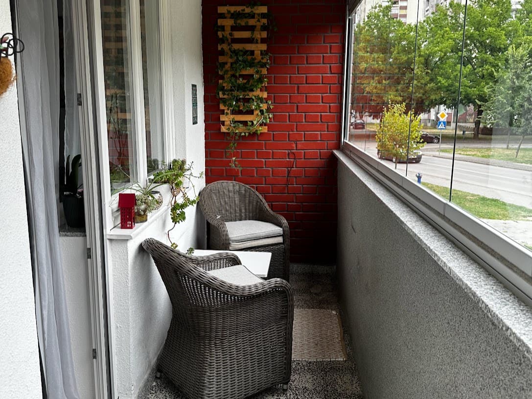 Balkon sa pletenim stolicama i crvenim zidom od cigle